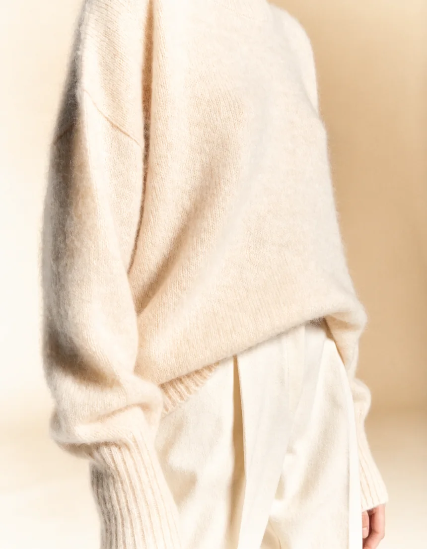 A model wearing an oversized cream cashmere jumper, shown from the chest down
